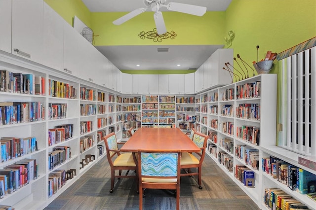 sitting room featuring a ceiling fan and bookshelves