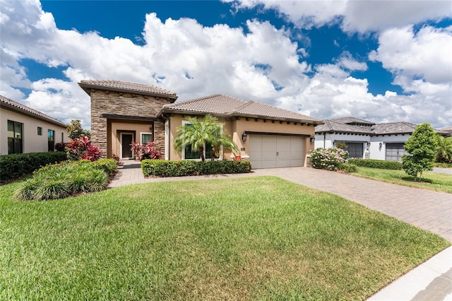 mediterranean / spanish house featuring stone siding, stucco siding, a garage, a tile roof, and driveway