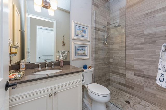 full bath featuring a tile shower, vanity, and toilet