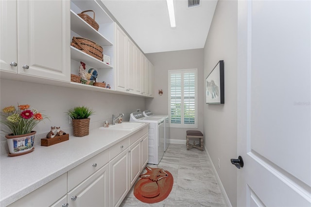 laundry area featuring light marble finish flooring, independent washer and dryer, cabinet space, and baseboards