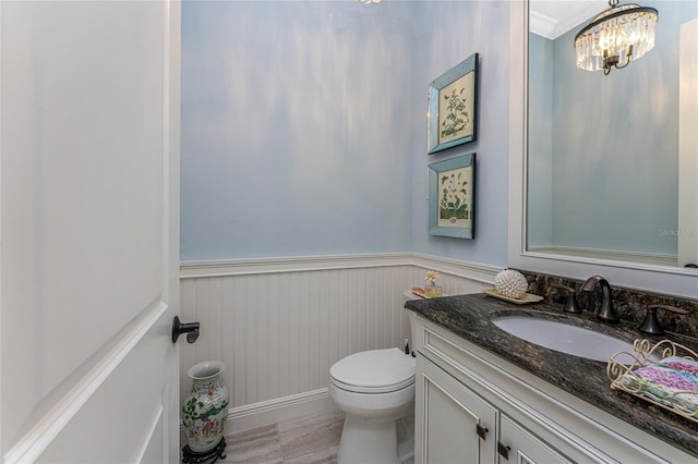 bathroom with vanity, a chandelier, toilet, and wainscoting
