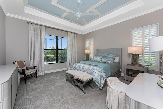 carpeted bedroom featuring a tray ceiling, ornamental molding, baseboards, and a ceiling fan