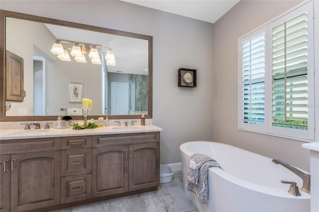bathroom featuring healthy amount of natural light, a soaking tub, double vanity, and baseboards