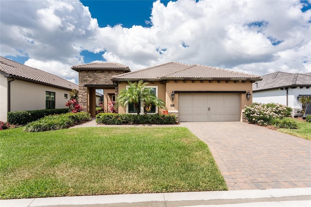 mediterranean / spanish-style home with stucco siding, a garage, a tiled roof, decorative driveway, and a front lawn