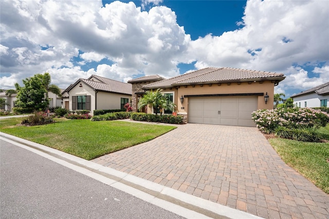 mediterranean / spanish-style home featuring stucco siding, a front lawn, a garage, and decorative driveway