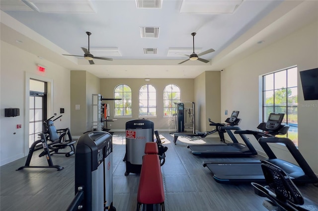 workout area featuring ceiling fan, baseboards, and a tray ceiling