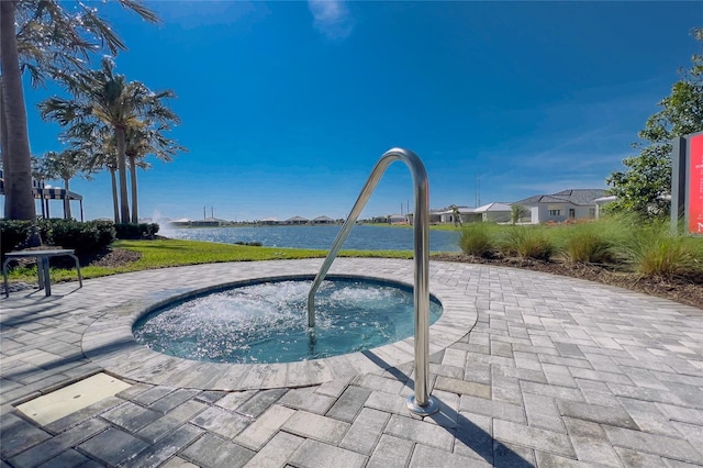 view of pool featuring an in-ground hot tub, a water view, and a patio
