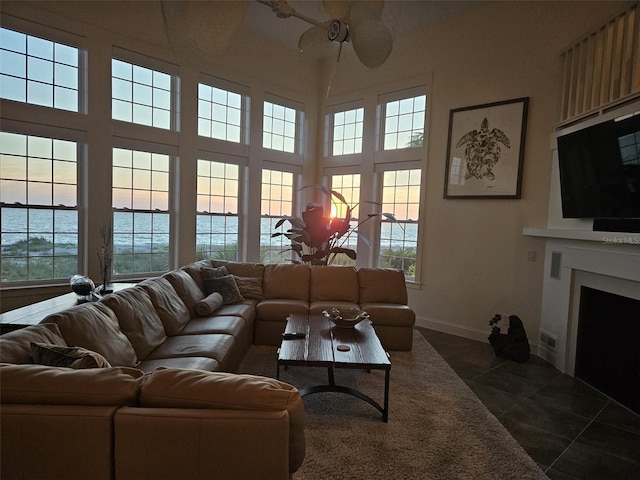 6890 Palm Island Dr, Placida, FL 33946 - living room featuring dark tile patterned floors, ceiling fan, baseboards, a high ceiling, and a fireplace with flush hearth