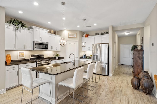 11125 Mcdermott Ct, Englewood, FL 34223 - kitchen with appliances with stainless steel finishes, a kitchen bar, a sink, and light wood-type flooring