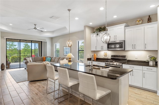 11125 Mcdermott Ct, Englewood, FL 34223 - kitchen featuring appliances with stainless steel finishes, a sink, white cabinets, open floor plan, and a breakfast bar