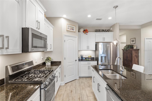 11125 Mcdermott Ct, Englewood, FL 34223 - kitchen featuring white cabinets, appliances with stainless steel finishes, a sink, dark stone counters, and visible vents
