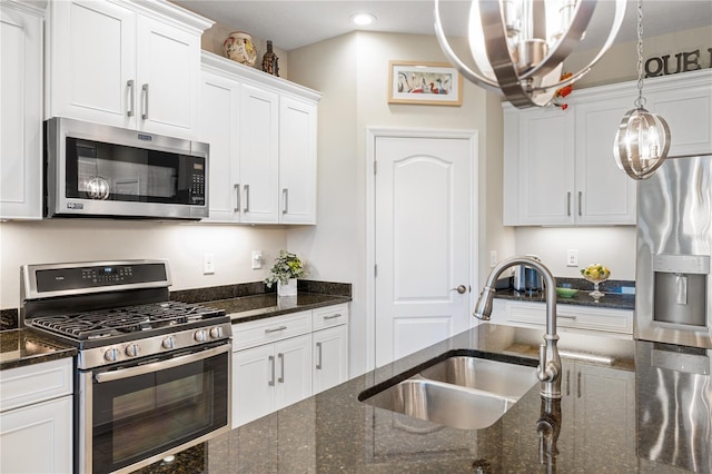 11125 Mcdermott Ct, Englewood, FL 34223 - kitchen with appliances with stainless steel finishes, a sink, white cabinets, dark stone countertops, and an inviting chandelier