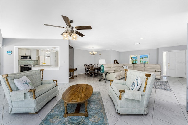 living area featuring light tile patterned floors, baseboards, and ceiling fan with notable chandelier