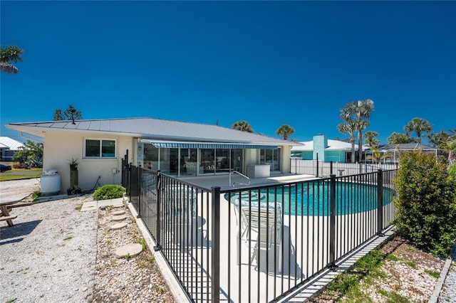 rear view of property with fence, stucco siding, a fenced in pool, a patio, and metal roof