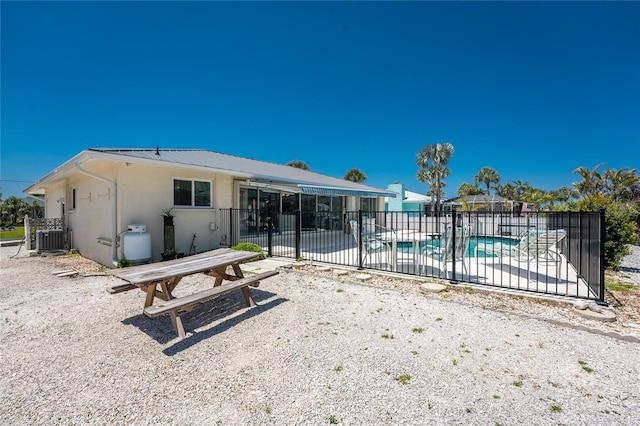 back of property with fence, stucco siding, a fenced in pool, central AC unit, and a patio area