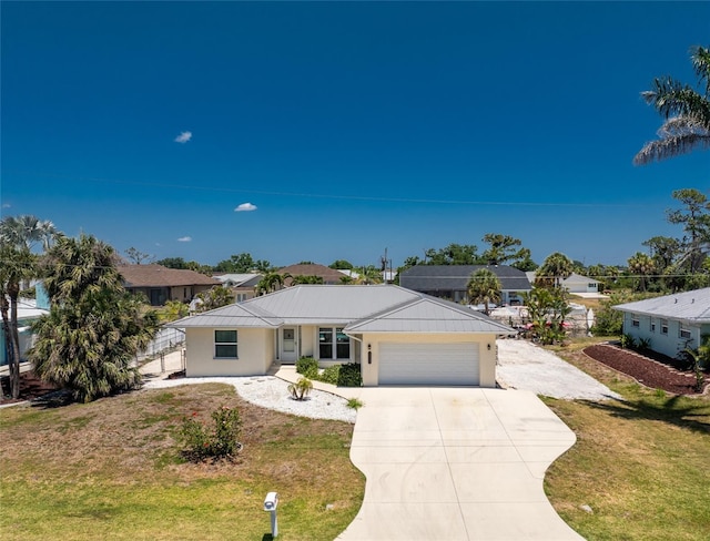 ranch-style home with concrete driveway, a garage, a front yard, and metal roof