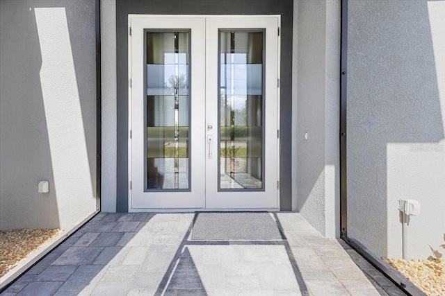 view of exterior entry with stucco siding and french doors