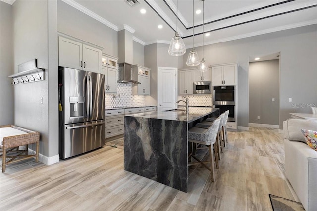 kitchen with crown molding, appliances with stainless steel finishes, light wood-style floors, a kitchen bar, and backsplash
