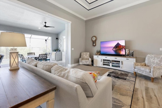 living area featuring a ceiling fan, baseboards, ornamental molding, and wood finished floors