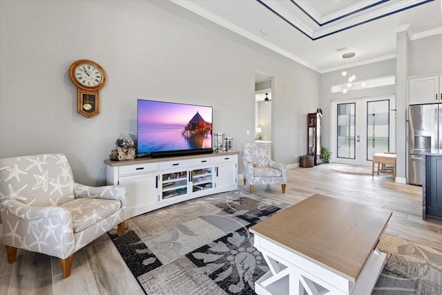 living area featuring crown molding, light wood finished floors, and a towering ceiling
