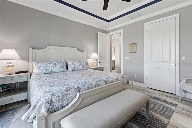bedroom featuring ceiling fan, visible vents, wood finished floors, baseboards, and ornamental molding