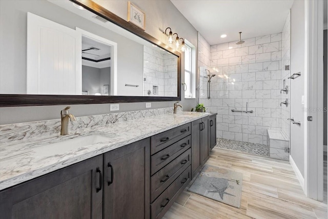 bathroom with wood finished floors, double vanity, a sink, and a stall shower