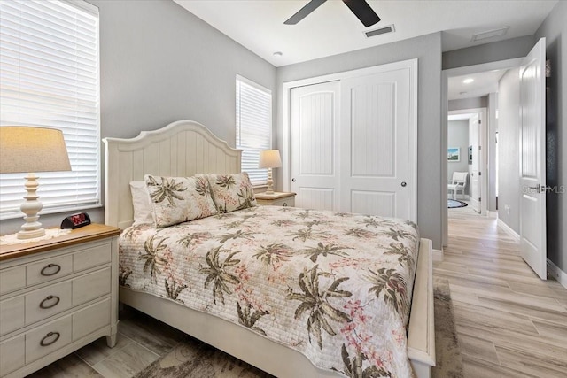 bedroom featuring visible vents, a closet, baseboards, ceiling fan, and light wood-style flooring