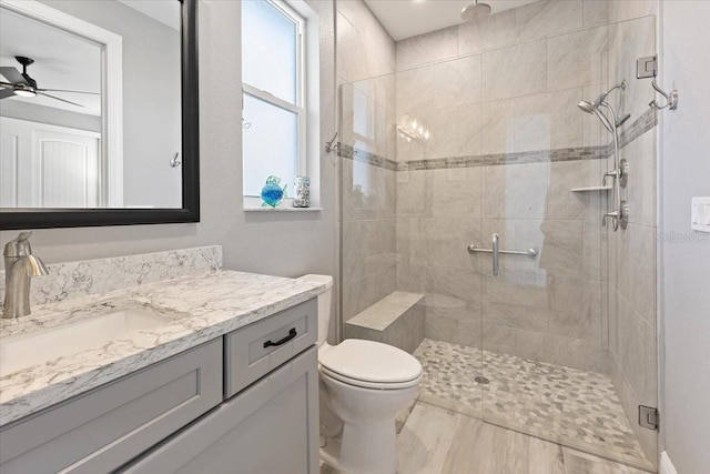 full bathroom featuring vanity, a ceiling fan, a shower stall, and toilet