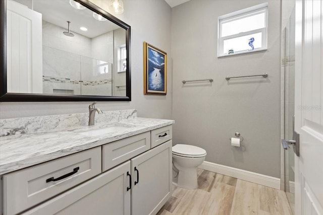 full bathroom with vanity, wood finished floors, toilet, baseboards, and a shower stall