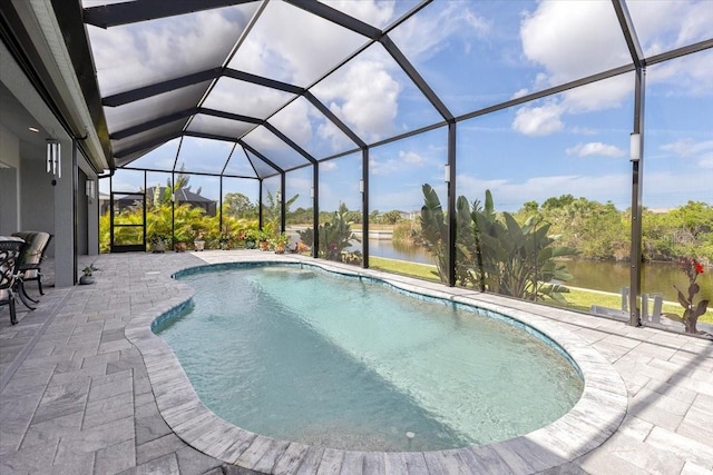 outdoor pool with glass enclosure, a patio, and a water view