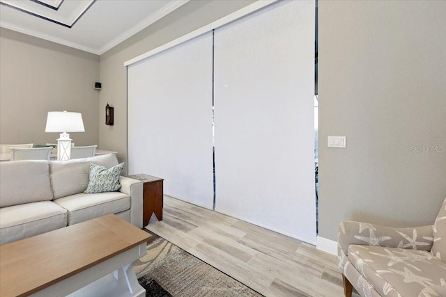 living room with crown molding, baseboards, and light wood-style flooring