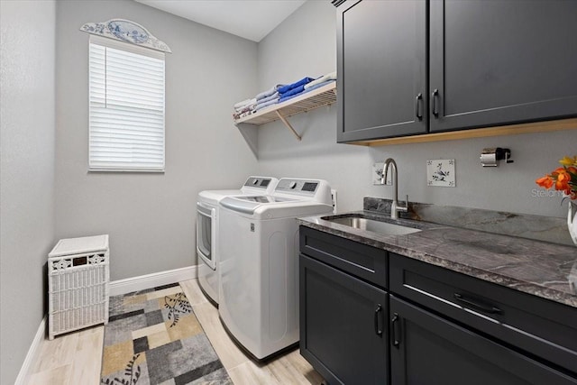 washroom featuring separate washer and dryer, a sink, cabinet space, and baseboards