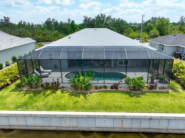 rear view of property featuring glass enclosure, a yard, a patio area, and an outdoor pool