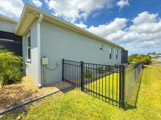 view of side of home with stucco siding, fence, and a yard