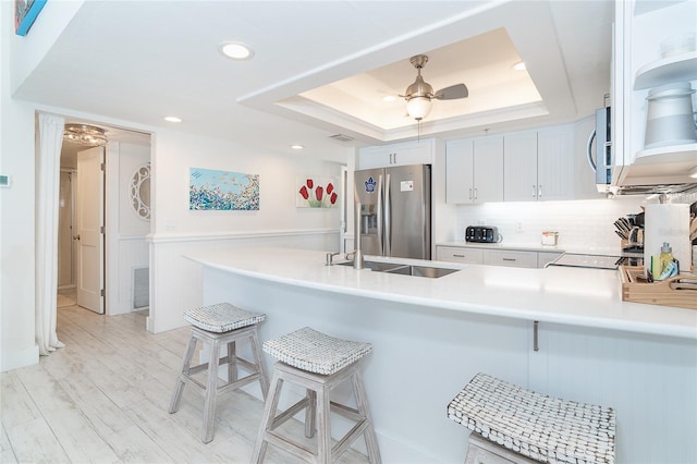 7548 Palm Island Dr S Unit 1724, Placida, FL 33946 - kitchen featuring appliances with stainless steel finishes, white cabinets, a peninsula, a breakfast bar, and a tray ceiling
