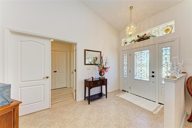 entrance foyer featuring an inviting chandelier, light tile patterned floors, a high ceiling, and baseboards
