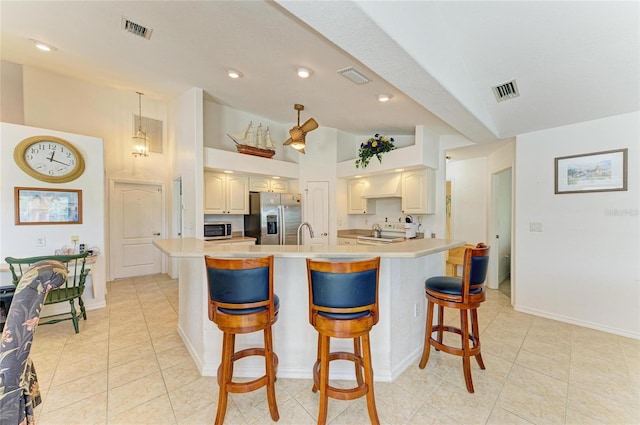 kitchen with light countertops, appliances with stainless steel finishes, a breakfast bar, and visible vents