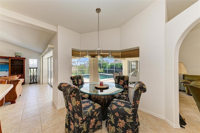 dining space with arched walkways, baseboards, vaulted ceiling, and light tile patterned flooring