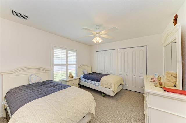 bedroom featuring a ceiling fan, two closets, light colored carpet, and visible vents