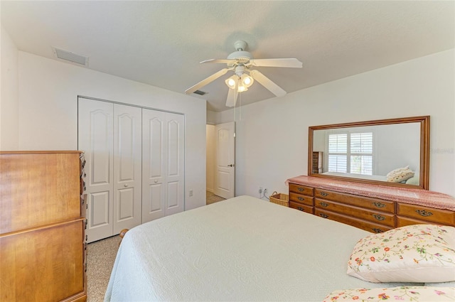 bedroom featuring light colored carpet, a ceiling fan, visible vents, and a closet
