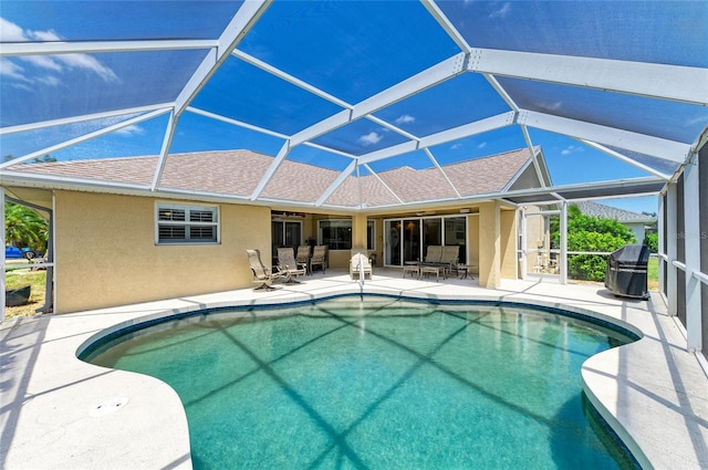 pool featuring glass enclosure, a patio area, and a grill