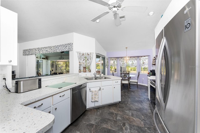 kitchen with lofted ceiling, light countertops, white cabinetry, a sink, and appliances with stainless steel finishes