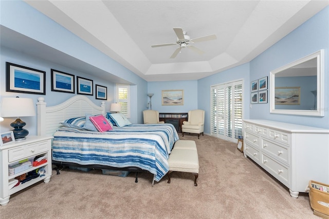 bedroom featuring a raised ceiling, ceiling fan, and light colored carpet