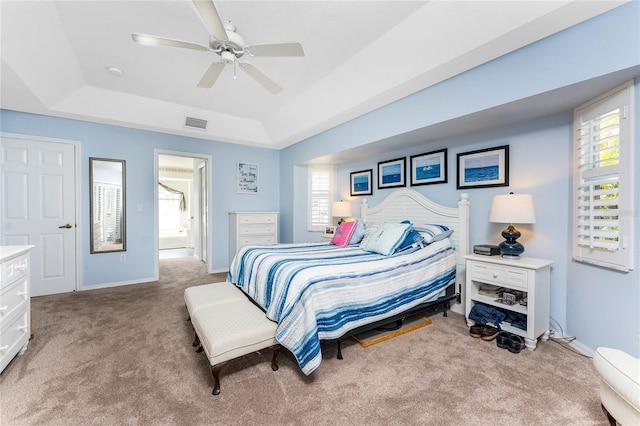 bedroom with carpet floors, visible vents, baseboards, ceiling fan, and a tray ceiling