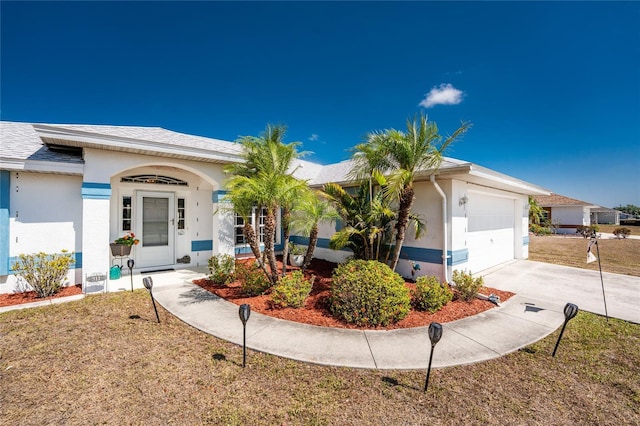 view of front of home with an attached garage, driveway, stucco siding, and a front yard
