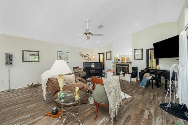living room featuring a ceiling fan, visible vents, a tiled fireplace, wood finished floors, and lofted ceiling