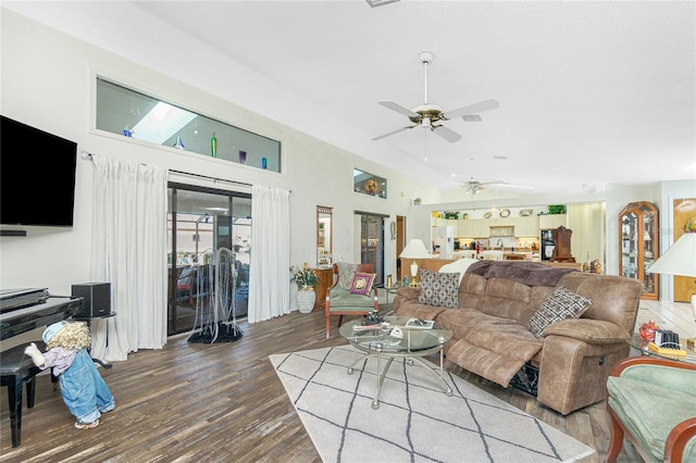 living area with ceiling fan, wood finished floors, and a high ceiling