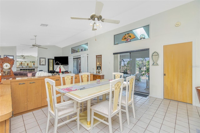dining room with ceiling fan, light tile patterned flooring, and vaulted ceiling