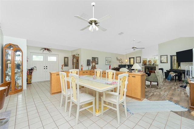 dining space with ceiling fan, vaulted ceiling, light tile patterned floors, and visible vents