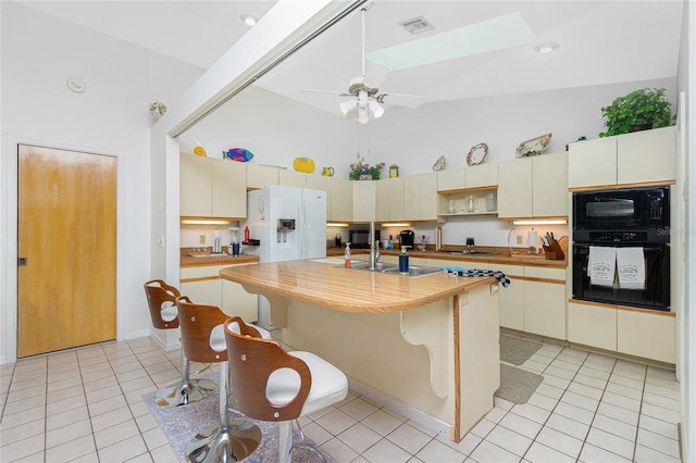 kitchen with a skylight, black appliances, light tile patterned flooring, and visible vents